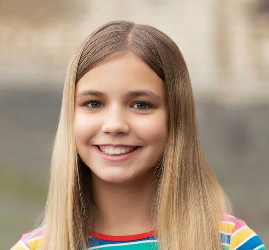 A young girl with long blonde hair is smiling for the camera.