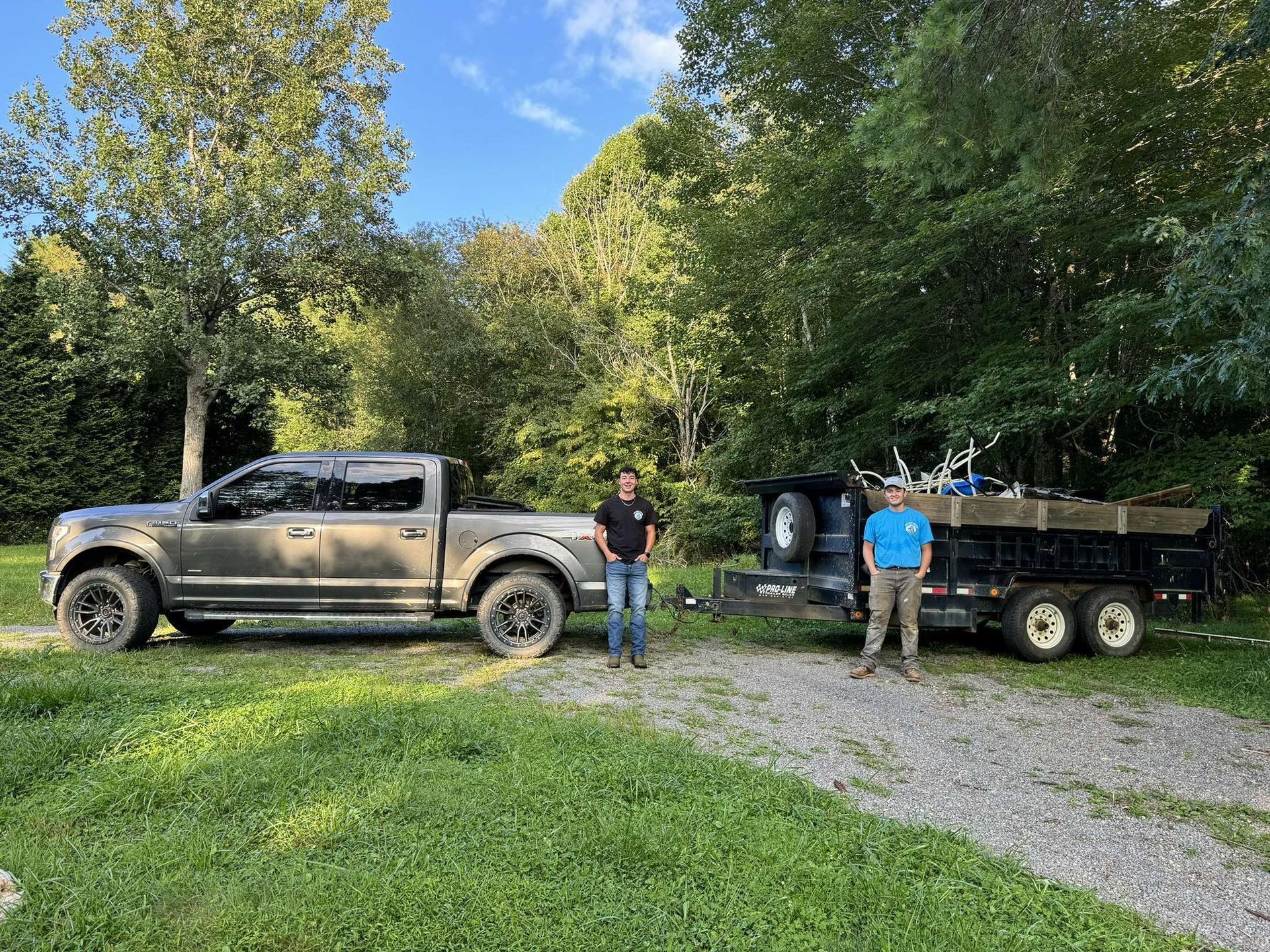 Two men are standing next to a truck and trailer.