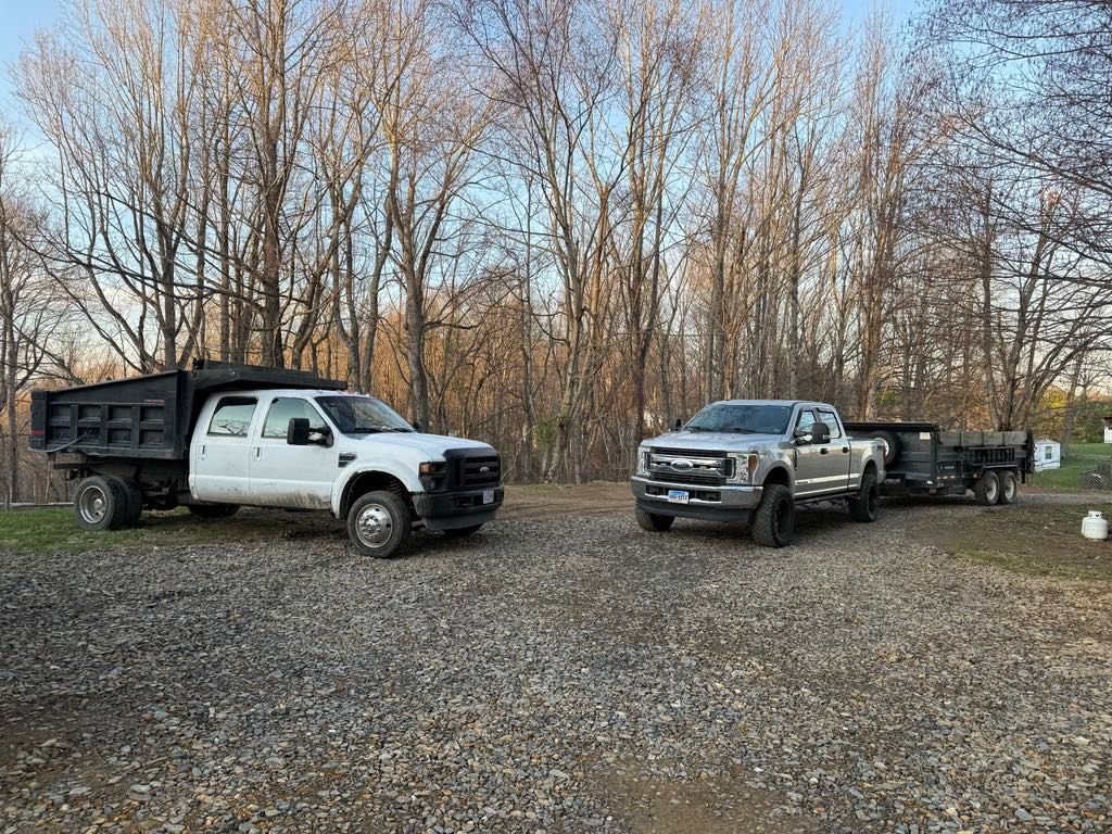 Two dump trucks are parked next to each other in a gravel lot.