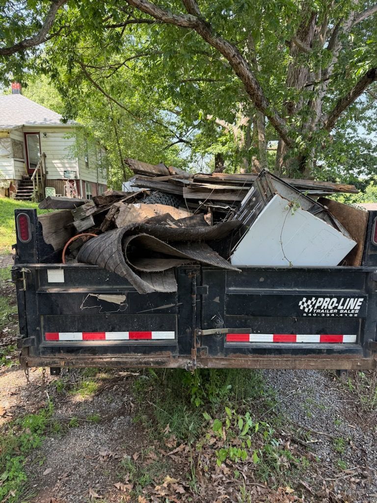 A dumpster filled with junk is parked in front of a house.