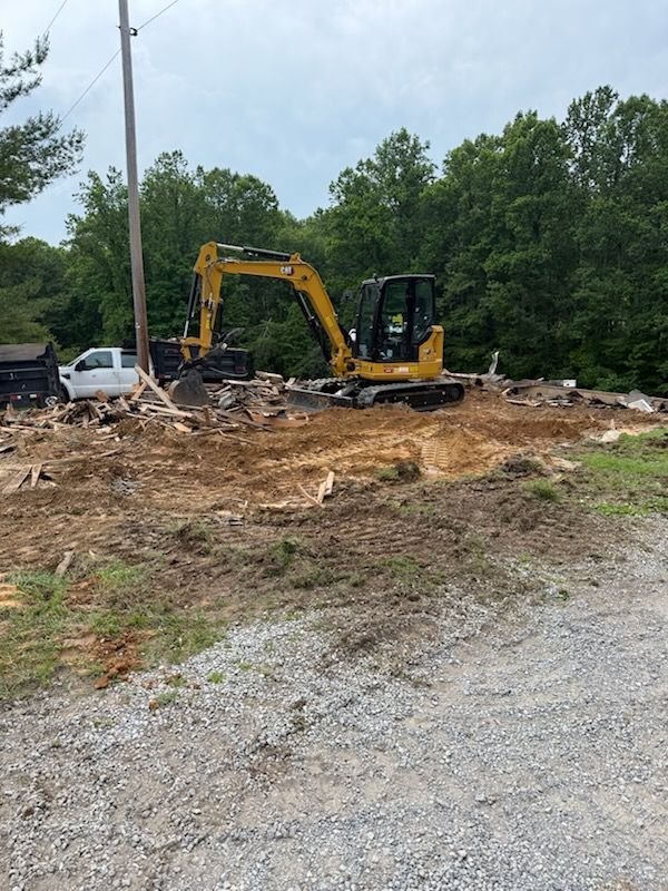 A yellow excavator is sitting in the middle of a dirt field.