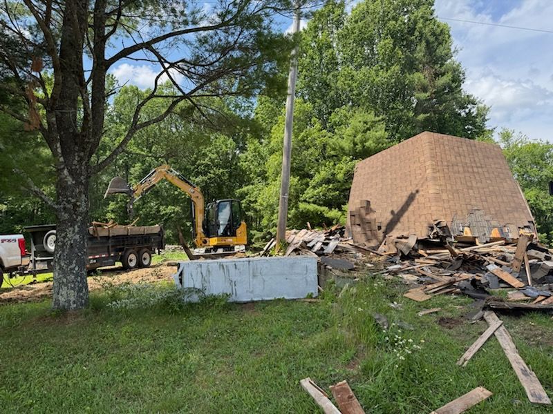 A bulldozer is demolishing a building in the middle of a field.