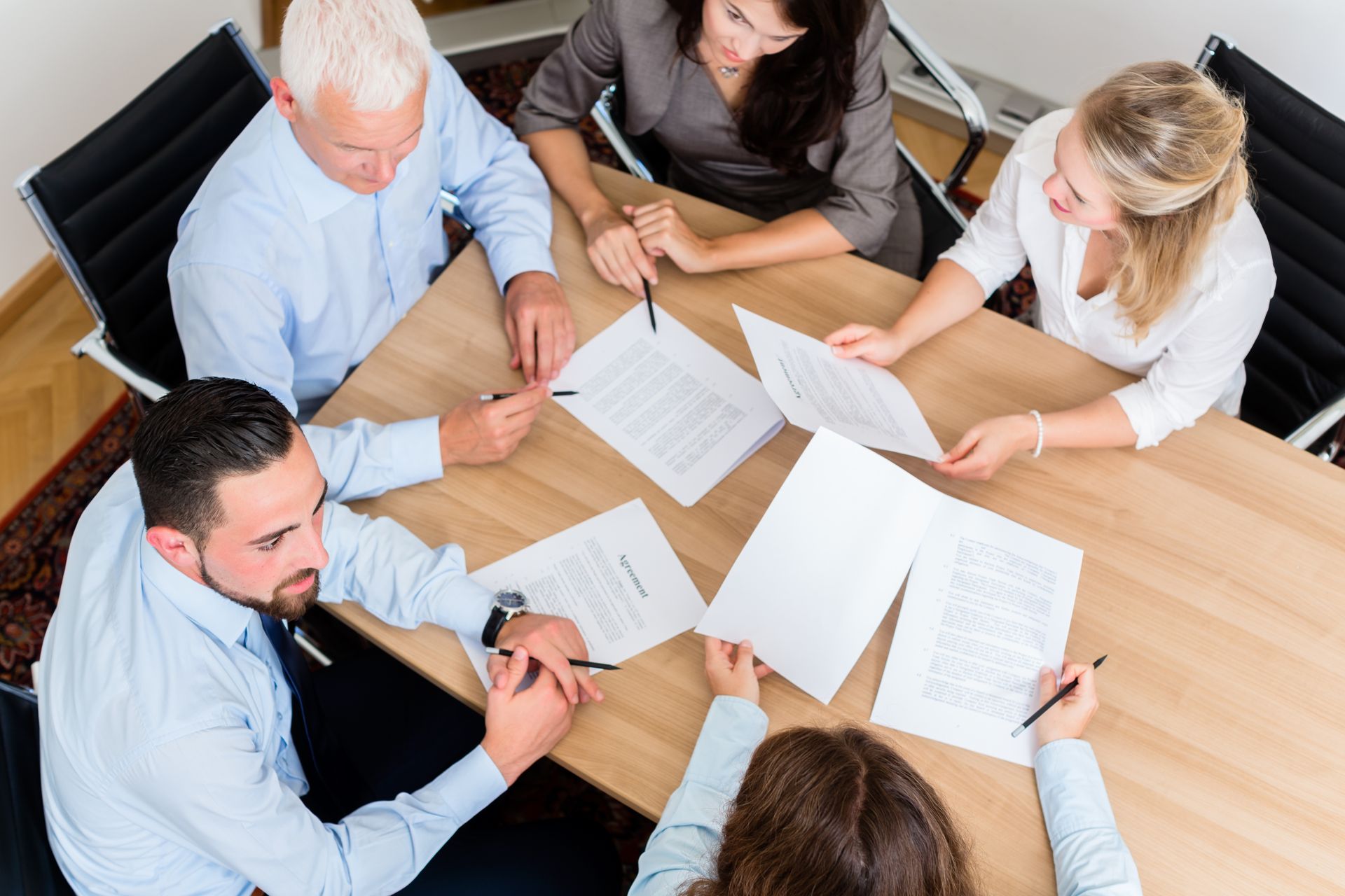 A group of people are sitting around a table looking at papers.