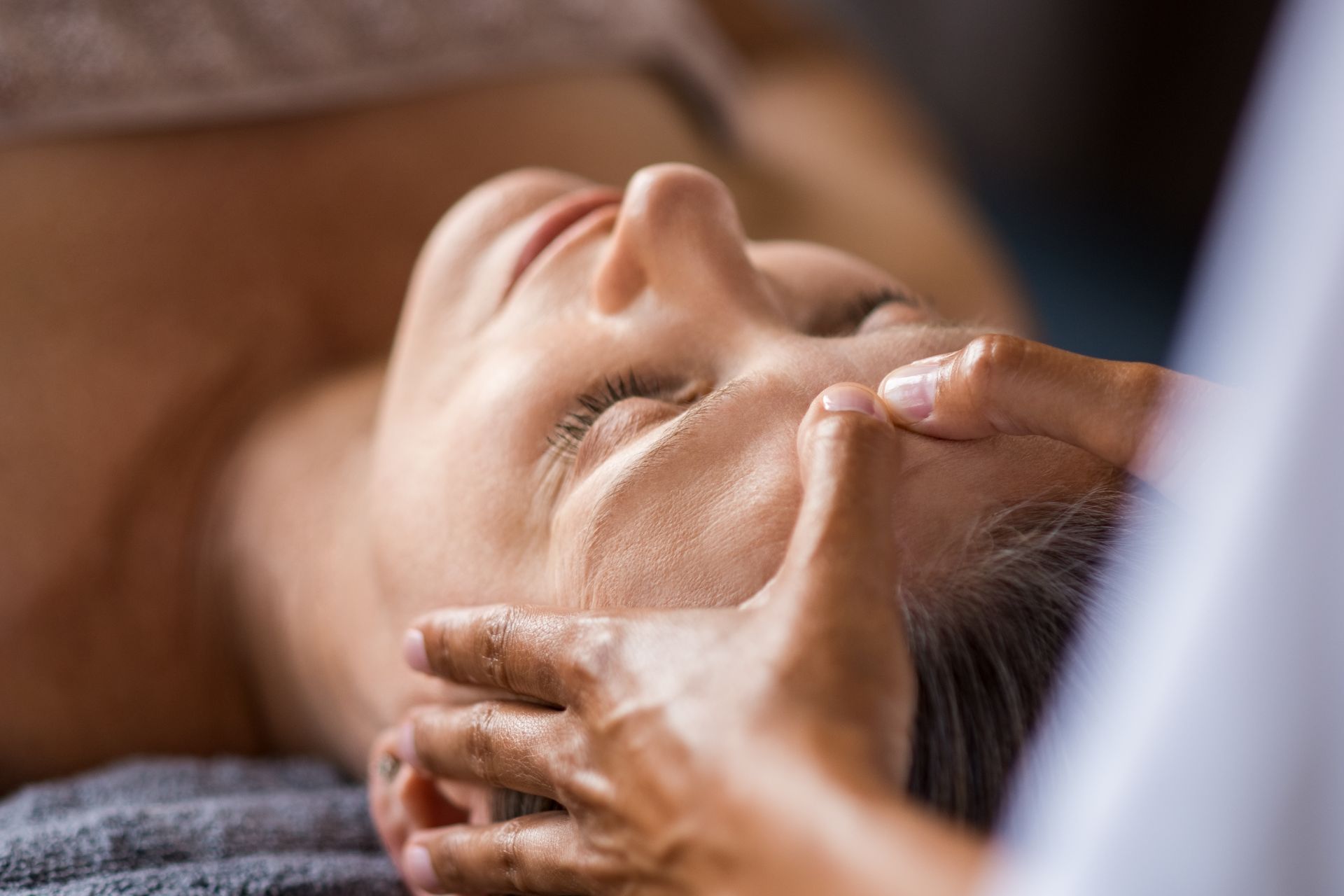 Una mujer está recibiendo un masaje de cabeza en un spa.