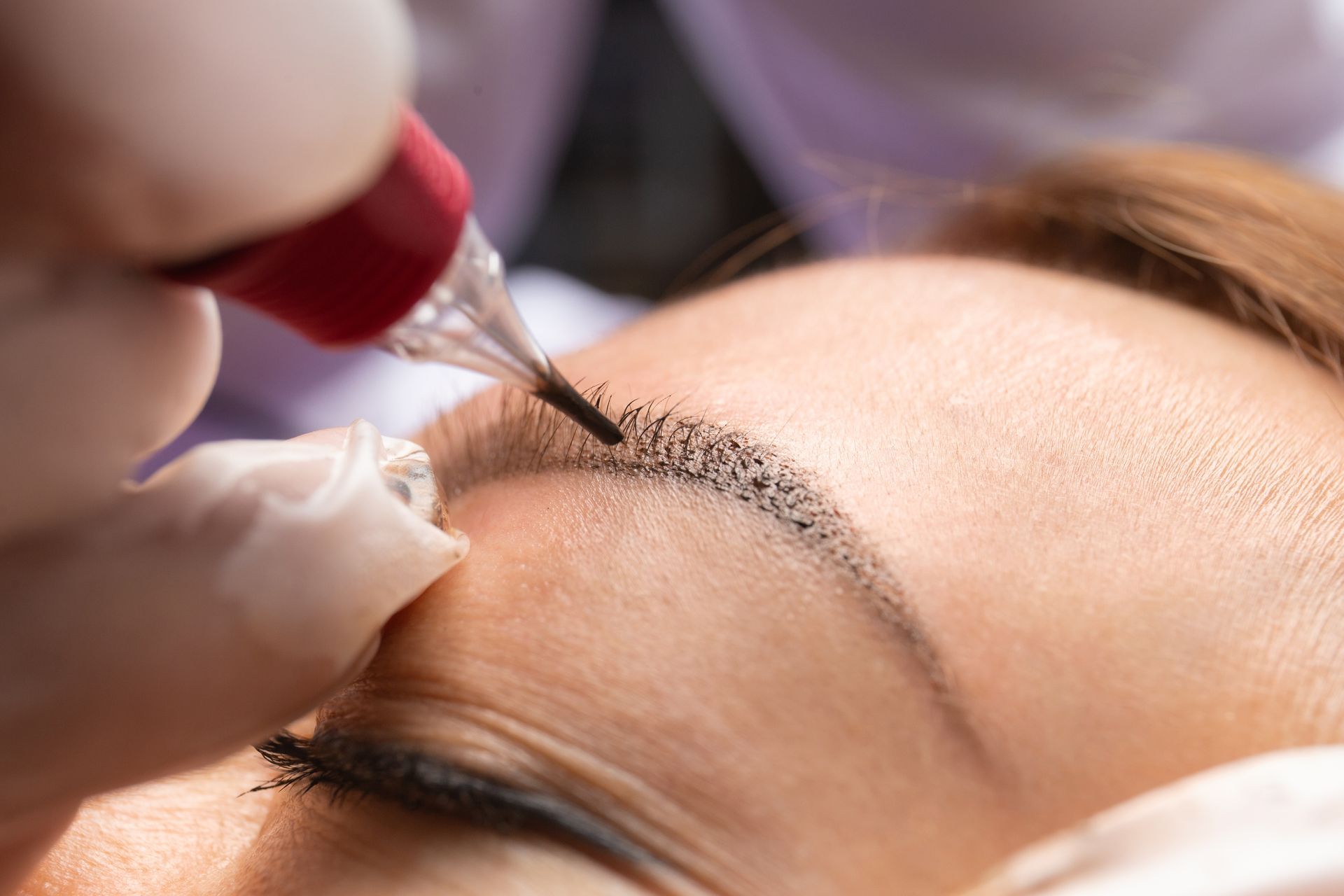 Una mujer se está haciendo un tatuaje de maquillaje permanente en las cejas.