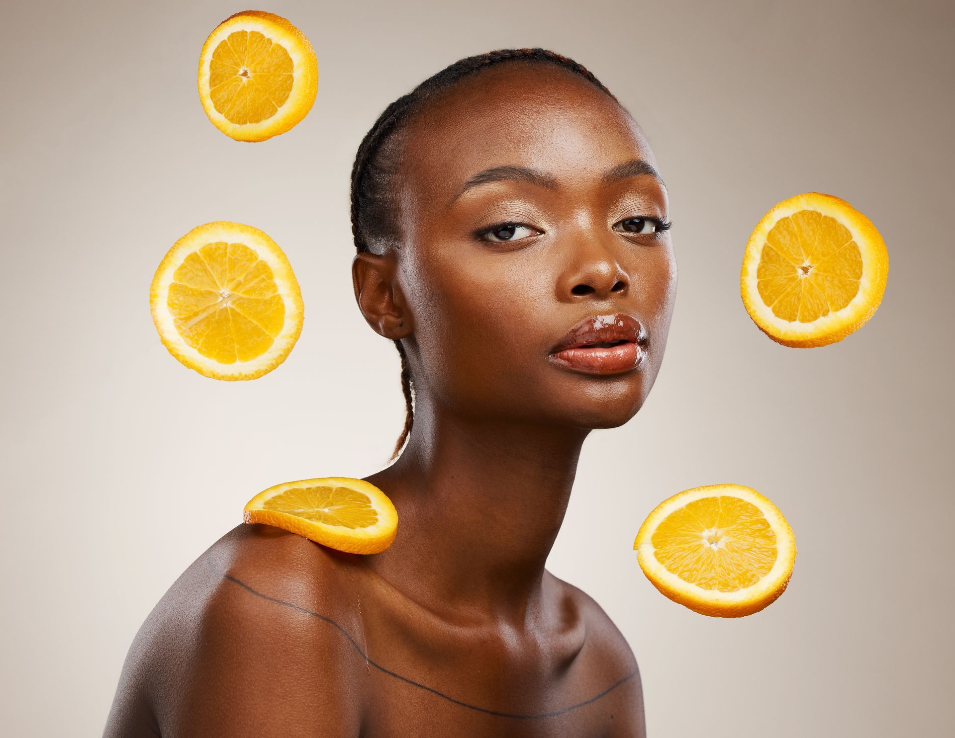 Una mujer con rodajas de naranja flotando alrededor de su cara.