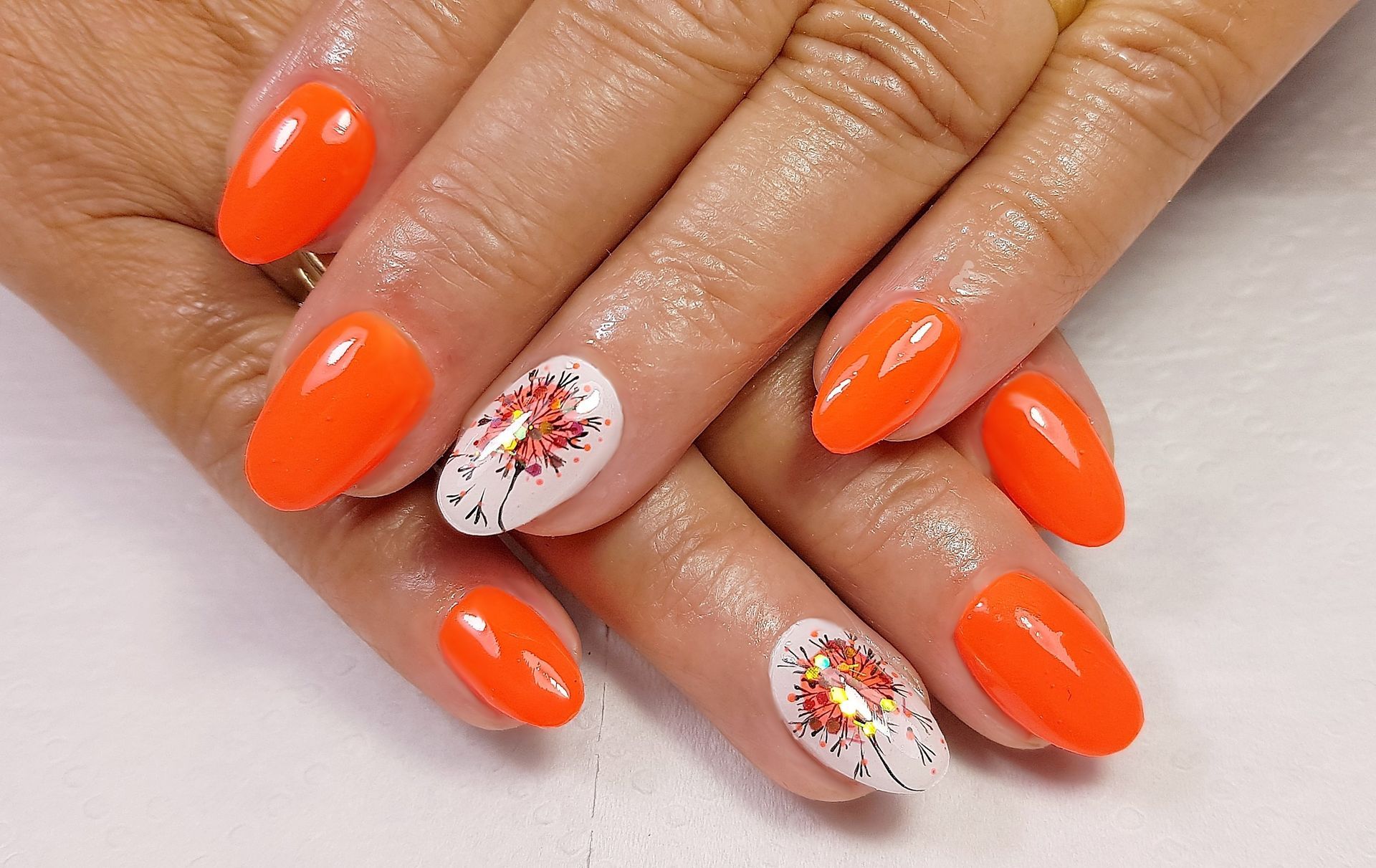 Un primer plano de las uñas de una mujer con uñas anaranjadas y blancas.