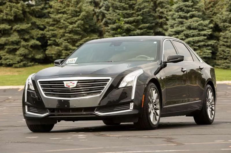 A black cadillac is parked in a parking lot.