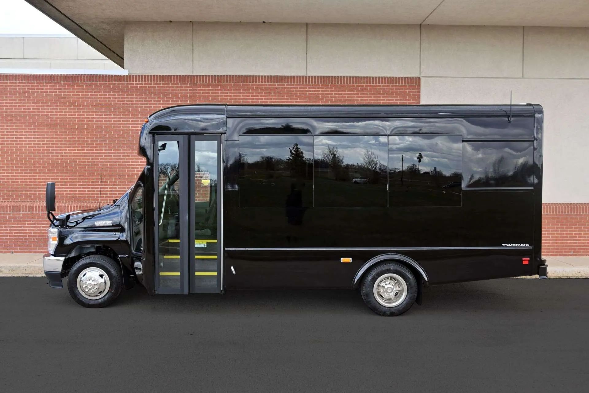 A black van is parked in front of a brick building.