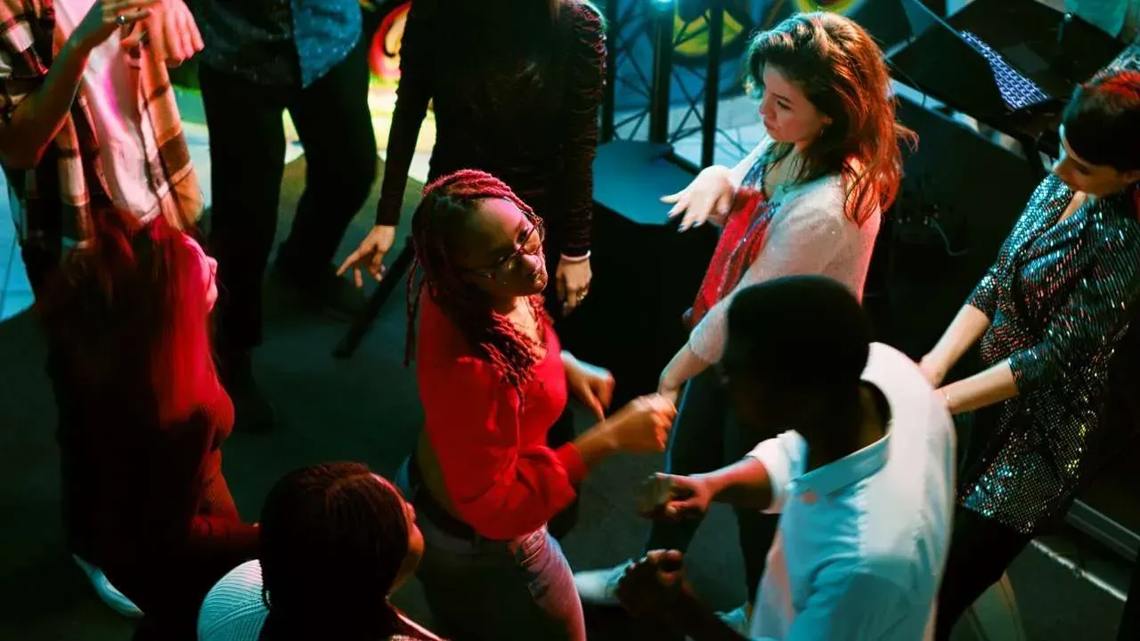 A group of people are dancing in a circle at a party.