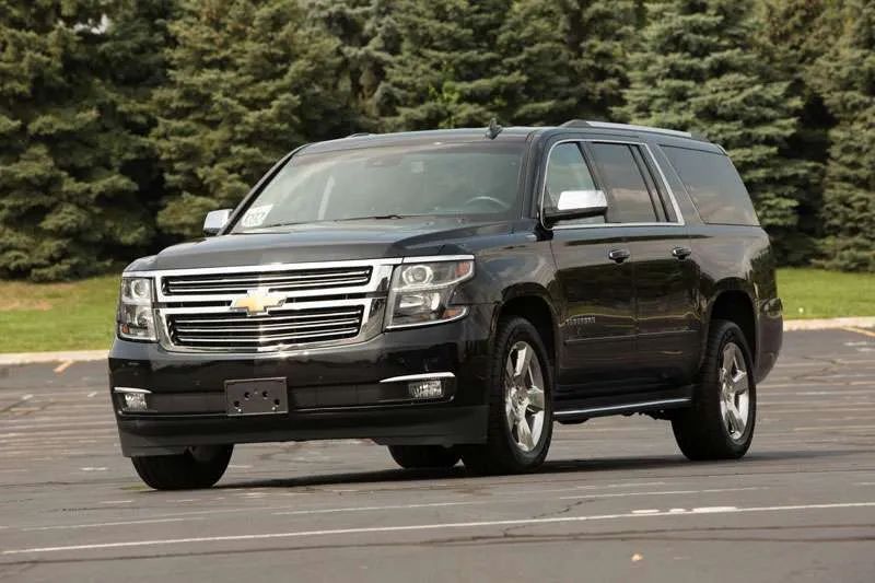A black chevrolet suburban suv is parked in a parking lot.