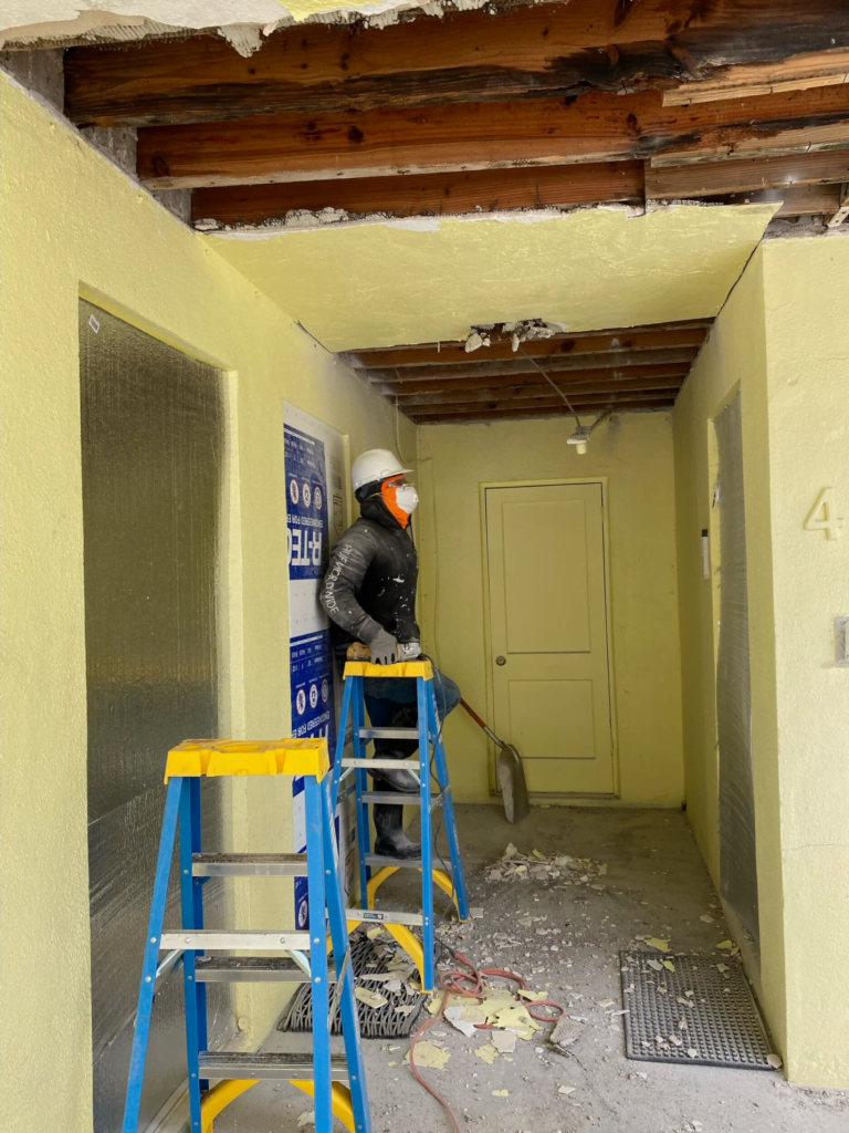 A man is standing on a ladder in a hallway.