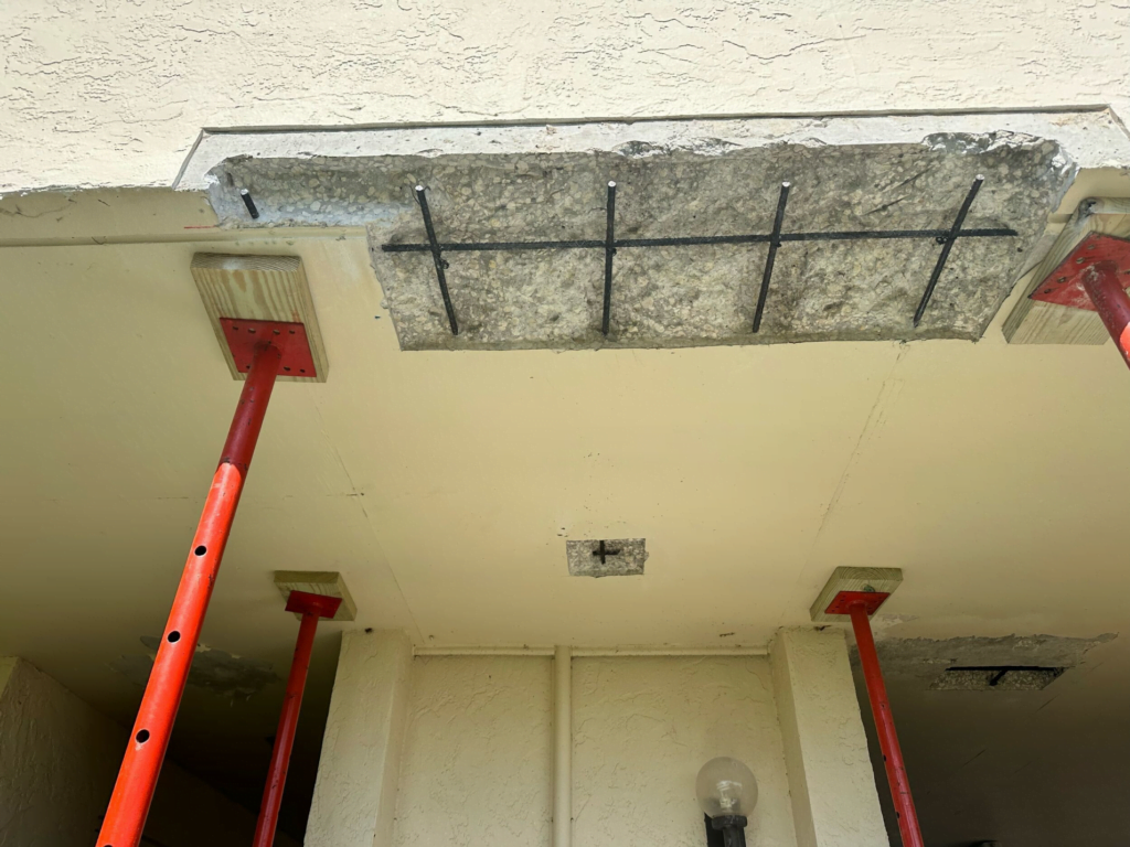 A concrete slab is being supported by red poles.