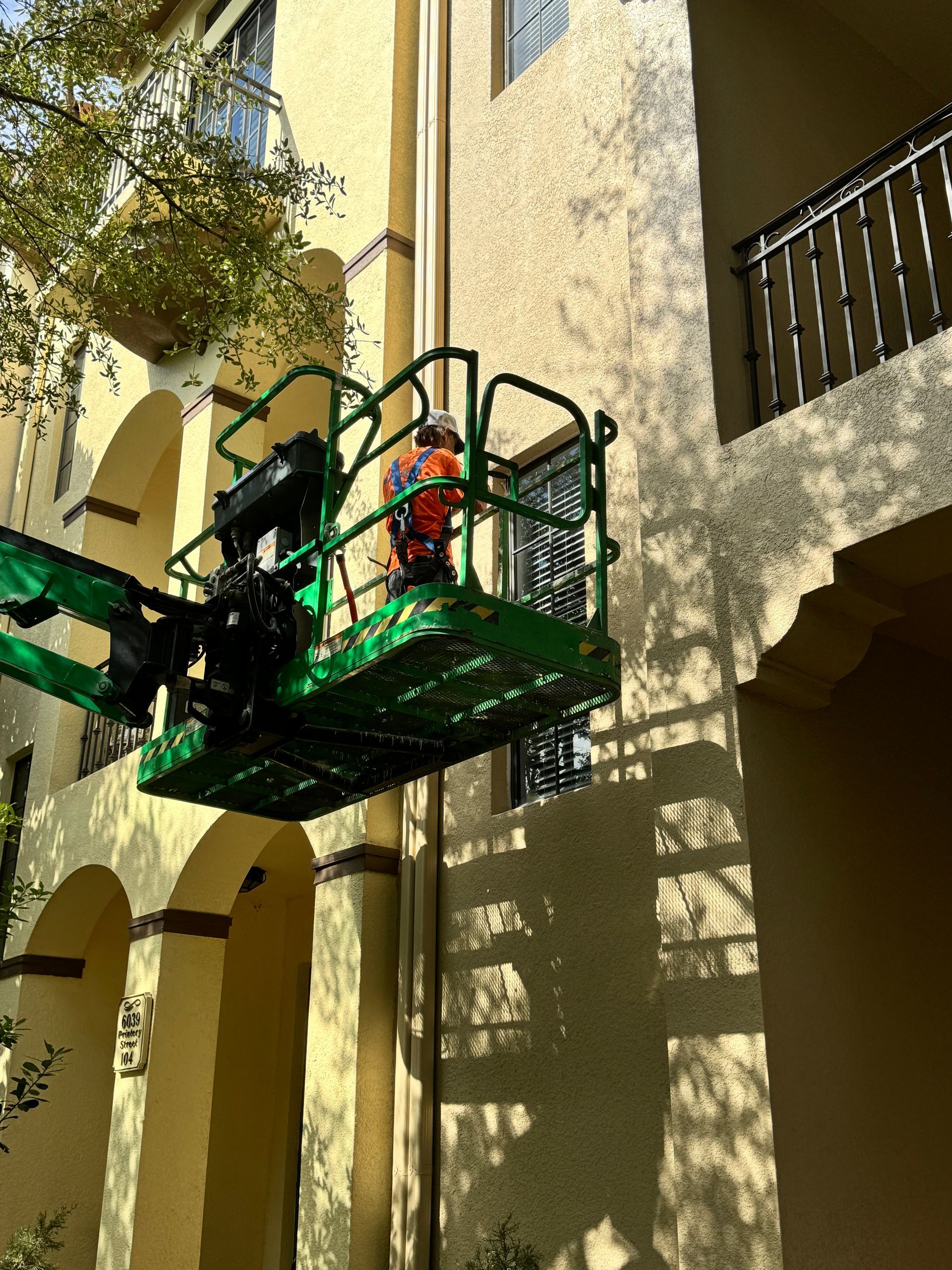 A man is standing in a green lift on the side of a building.