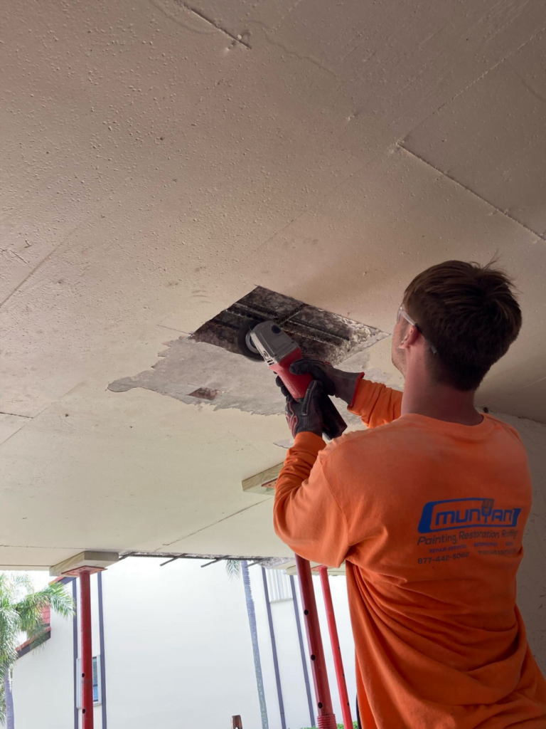 A man in an orange shirt is working on a ceiling