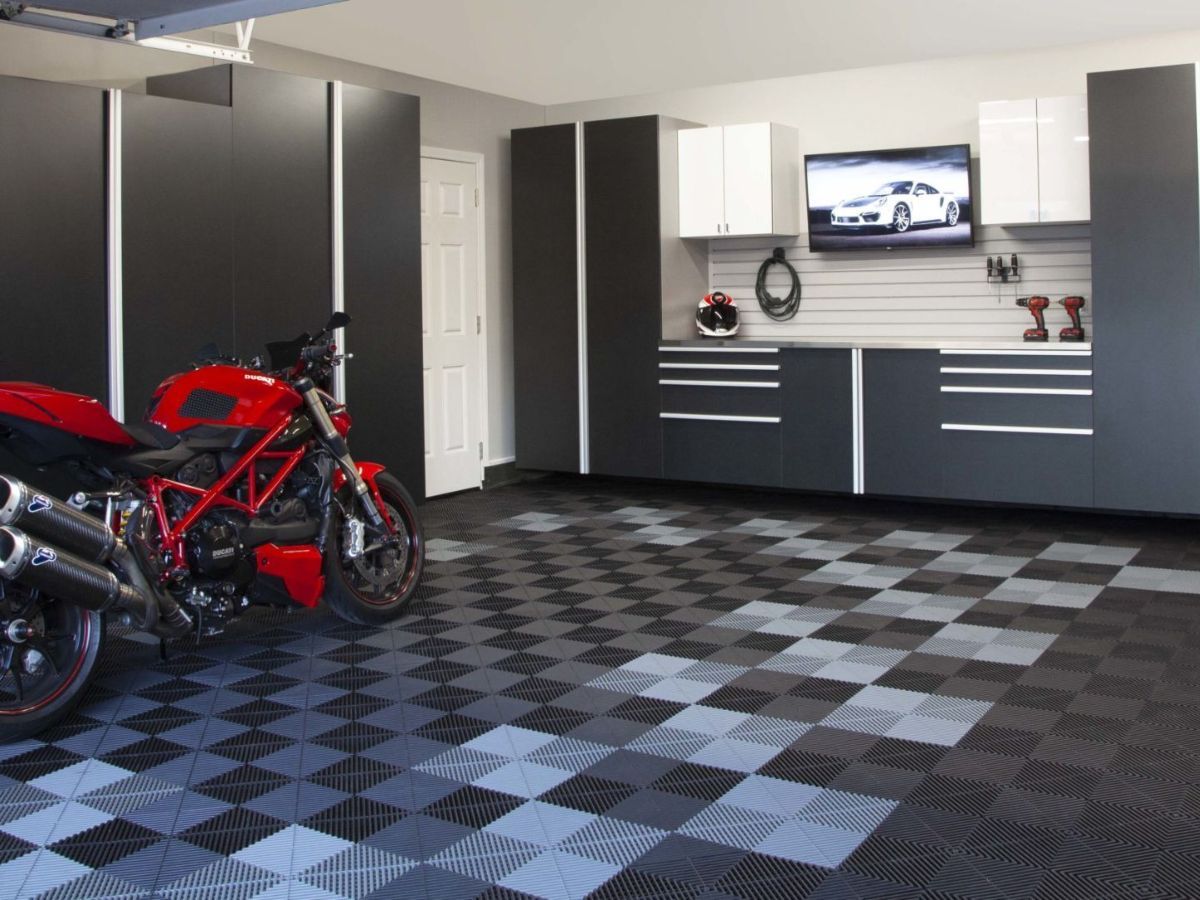 Red motorcycle parked in a modern garage with gray cabinets, gray and white checkered floor, and a TV.