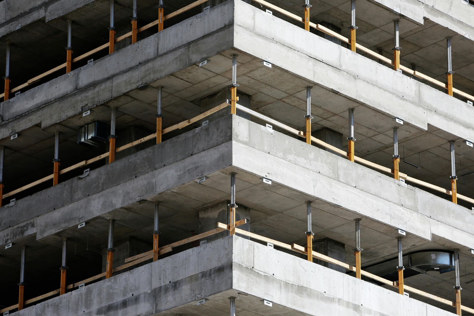 Bâtiment en construction ; planchers en béton soutenus par des poutres en bois, angle droit.