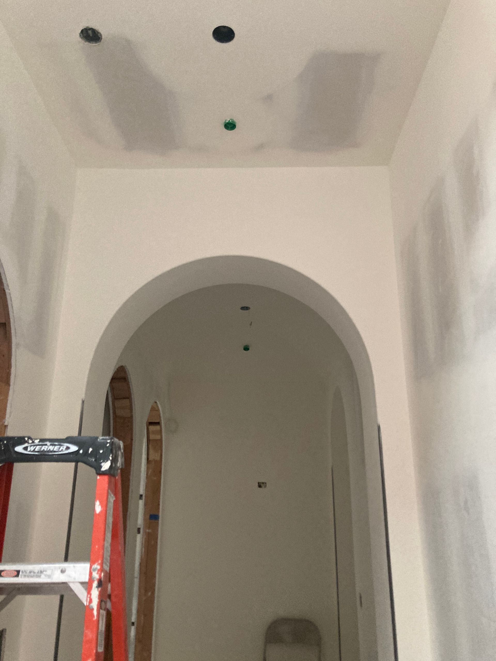 A ladder in a hallway with a ceiling that has holes in it