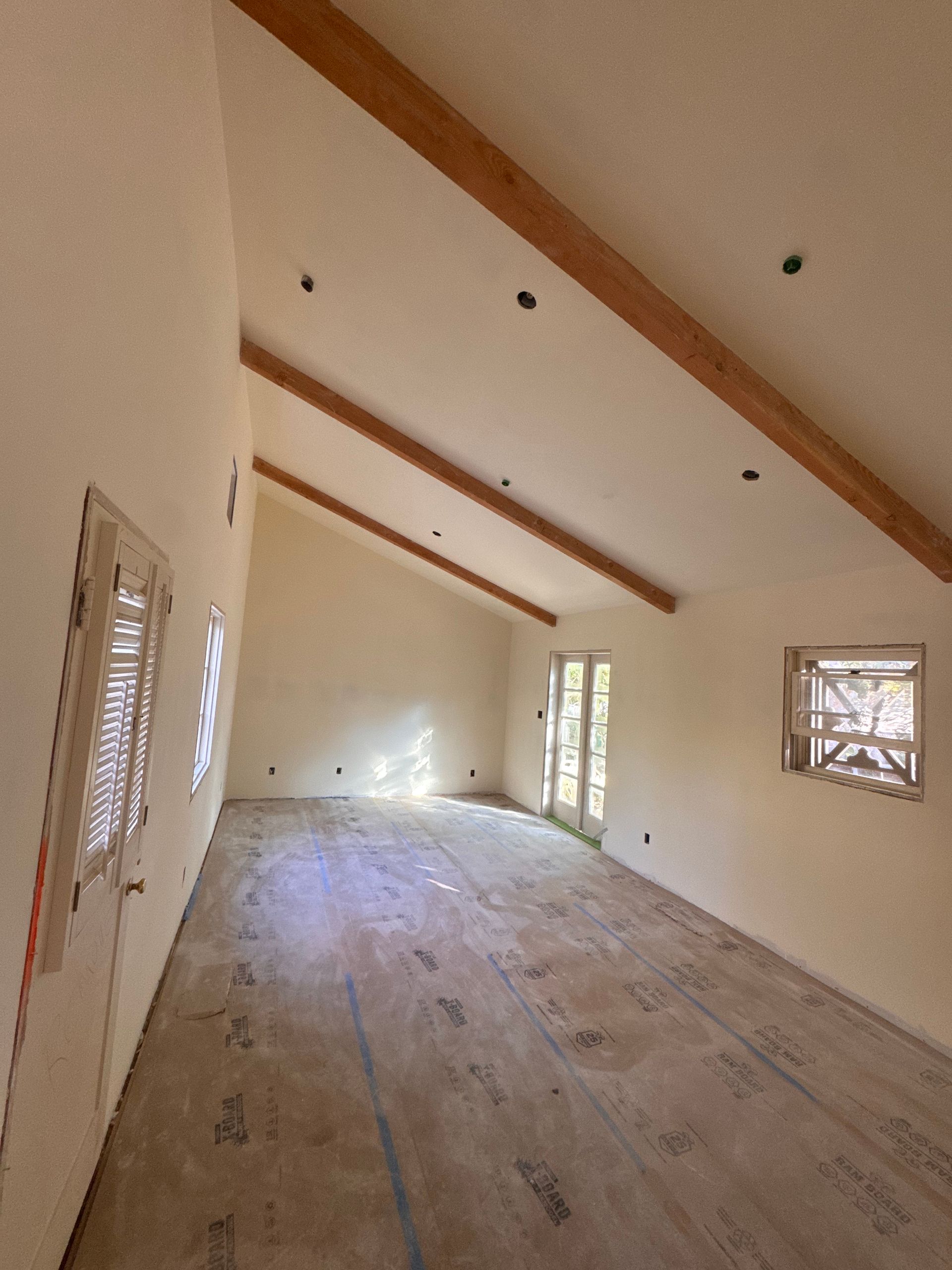 An empty room with a vaulted ceiling and wooden beams