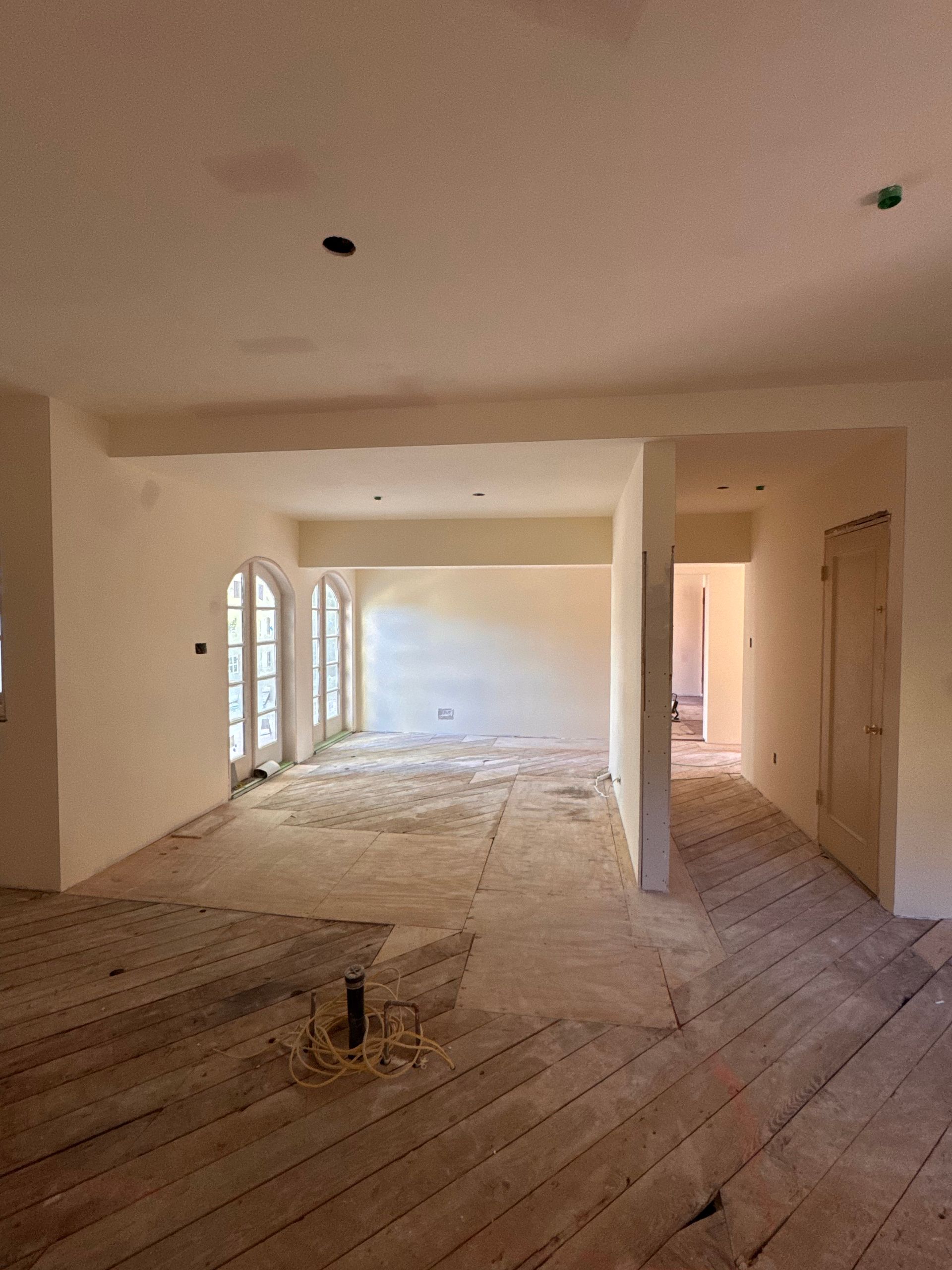 A large empty room with a wooden floor and white walls.