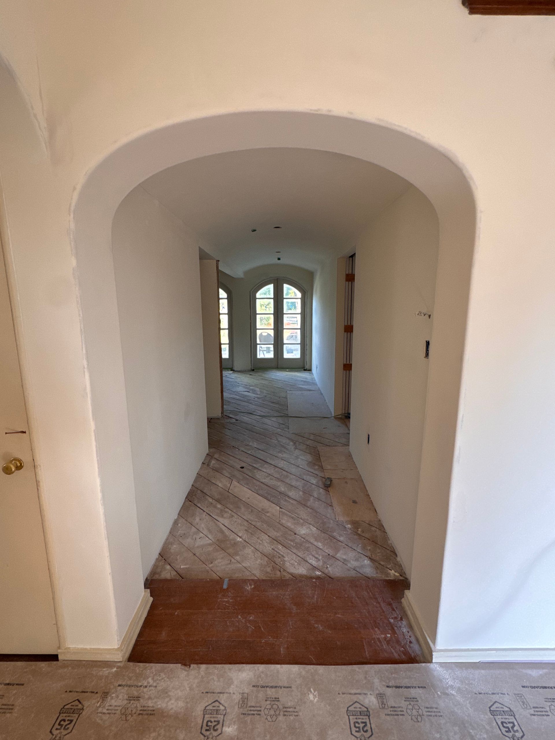 A hallway with a white archway leading to a window