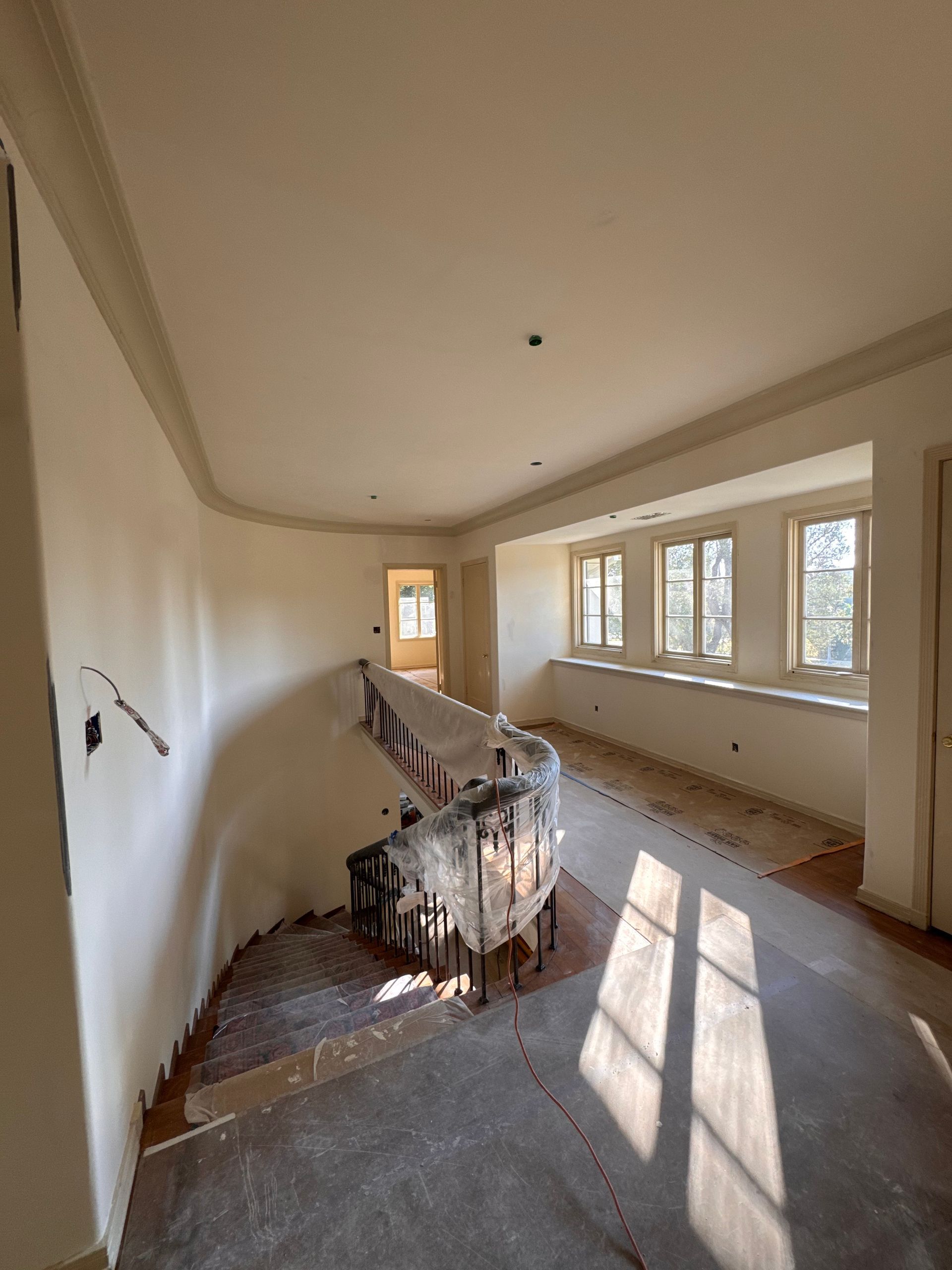 An empty room with a staircase and a lot of windows.