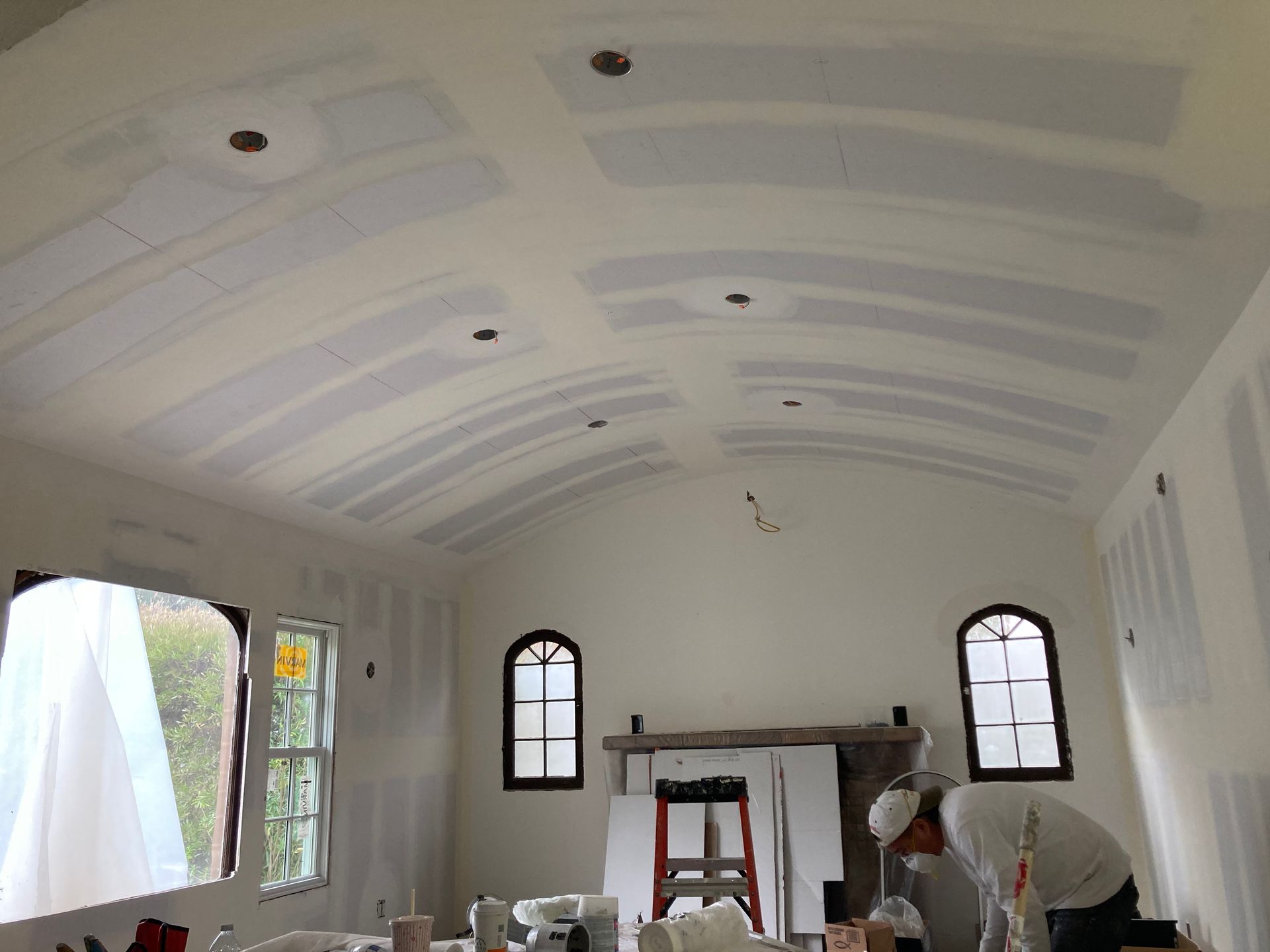 A man is working on the ceiling of a room