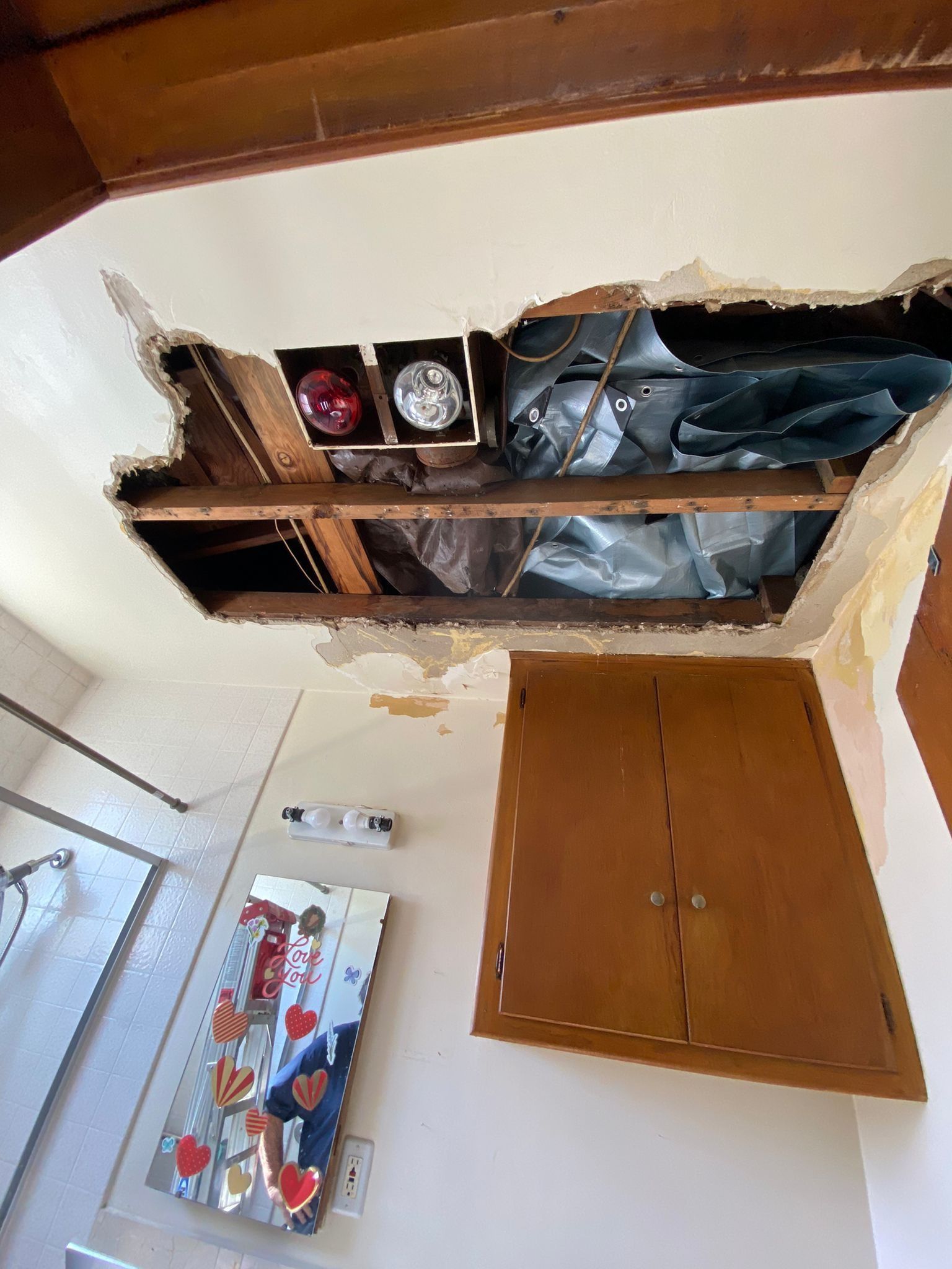A bathroom with a hole in the ceiling and a painting on the wall.