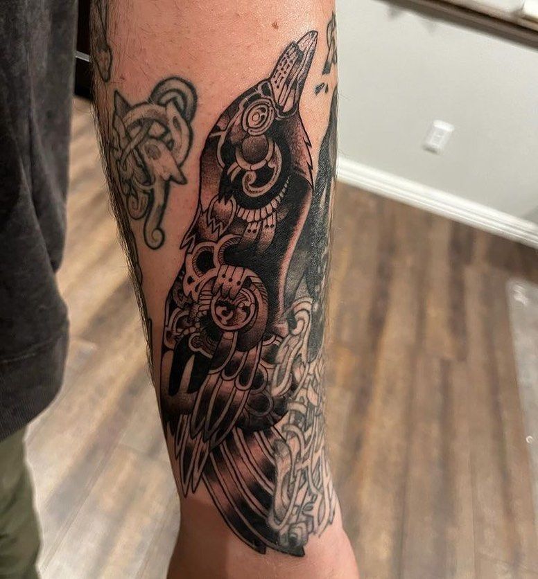 A man has a tattoo of a crow on his forearm.