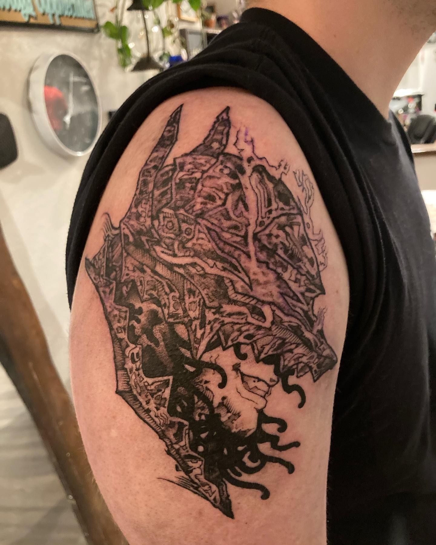 A man has a black and white tattoo on his shoulder