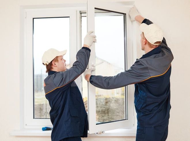 Two men are installing a window in a room.