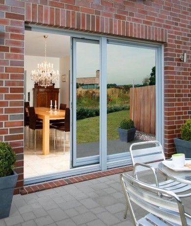 A brick building with a sliding glass door leading to a dining room