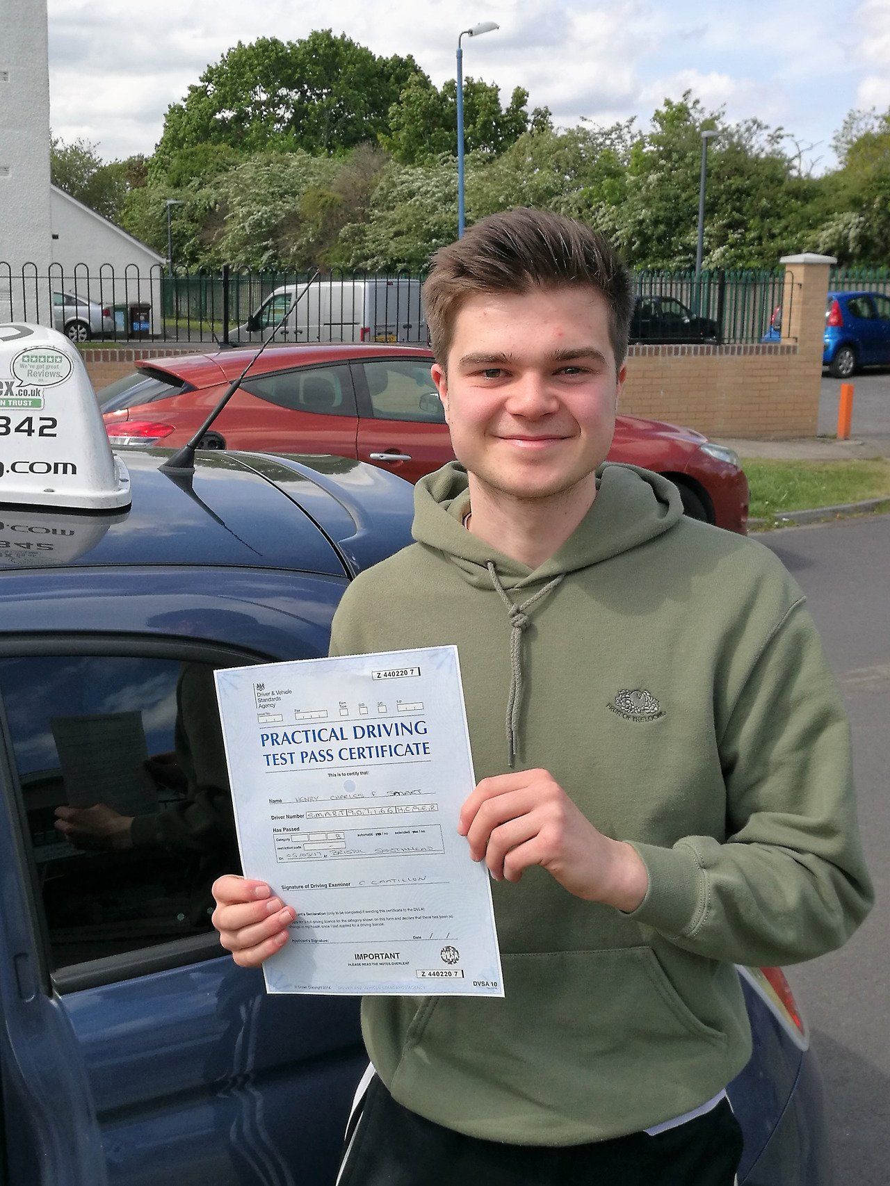 happy student passes his driving test and holds up her pass certificate to the camera