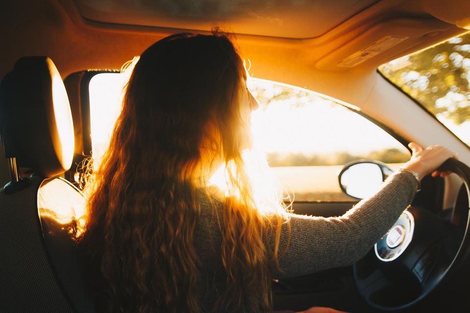 women driving a car with the sun behind her
