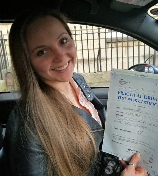 happy student passes her driving test and holds up her pass certificate to the camera