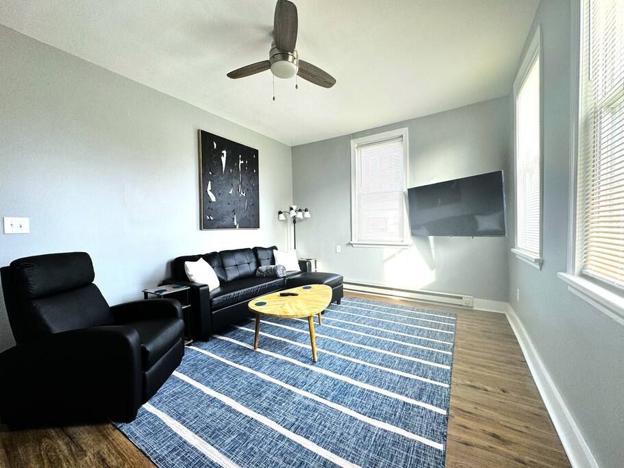 A living room with a couch , chairs , coffee table and ceiling fan.