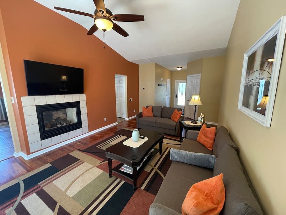 A living room with a couch , fireplace , coffee table and ceiling fan.
