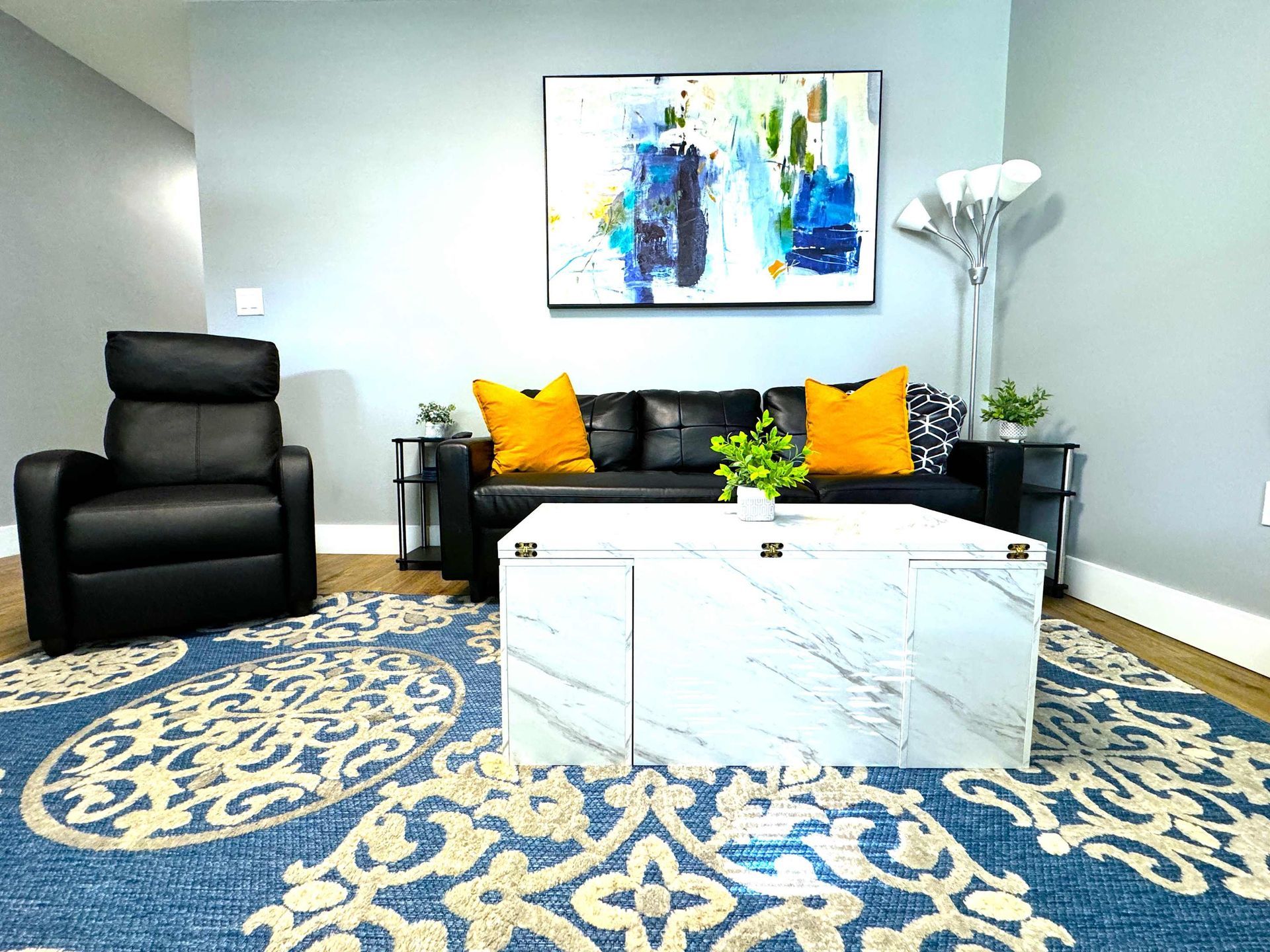 A living room with a couch , chair , coffee table and television.