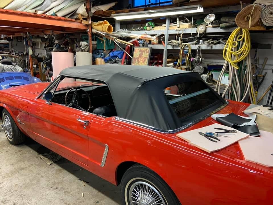 a red mustang convertible is parked in a garage .