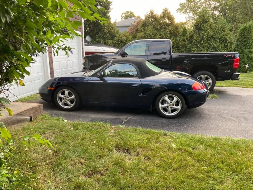 a silver convertible sports car is parked on the side of the road .