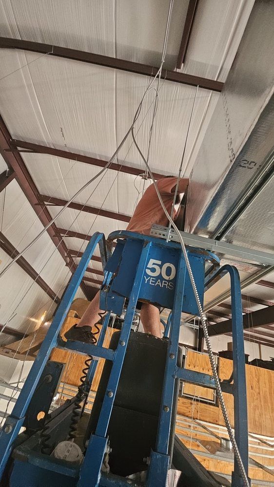 A person is standing on top of a blue ladder in a building.