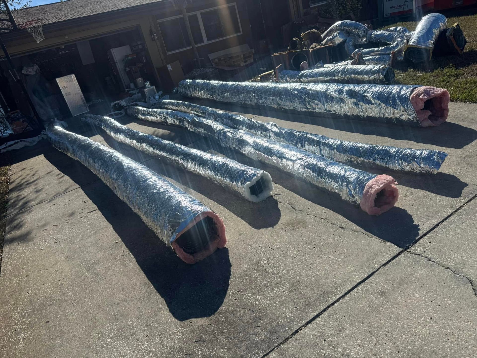 A bunch of ducts are sitting on the sidewalk in front of a house.