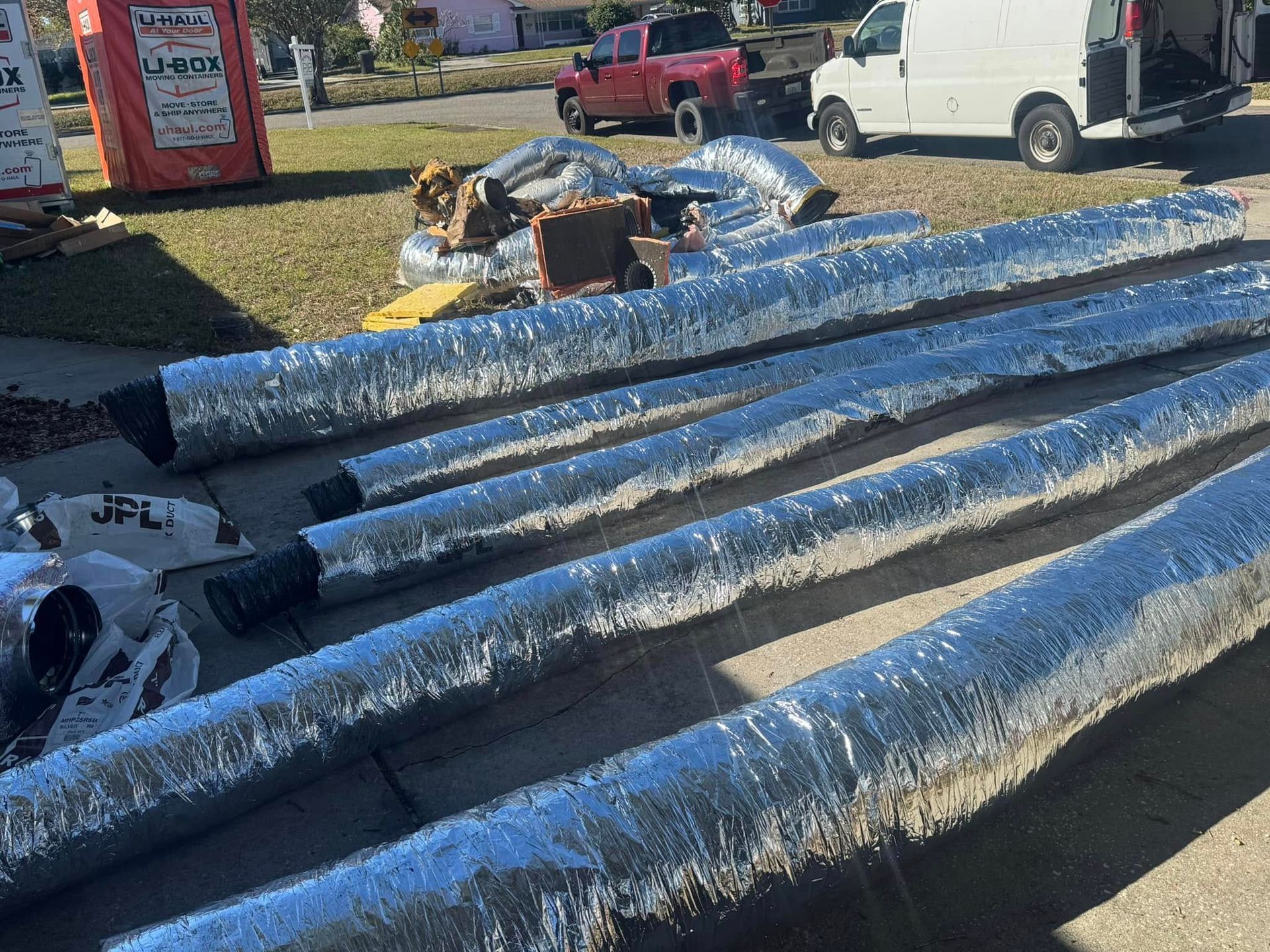 A bunch of ducts wrapped in foil are sitting on the sidewalk.
