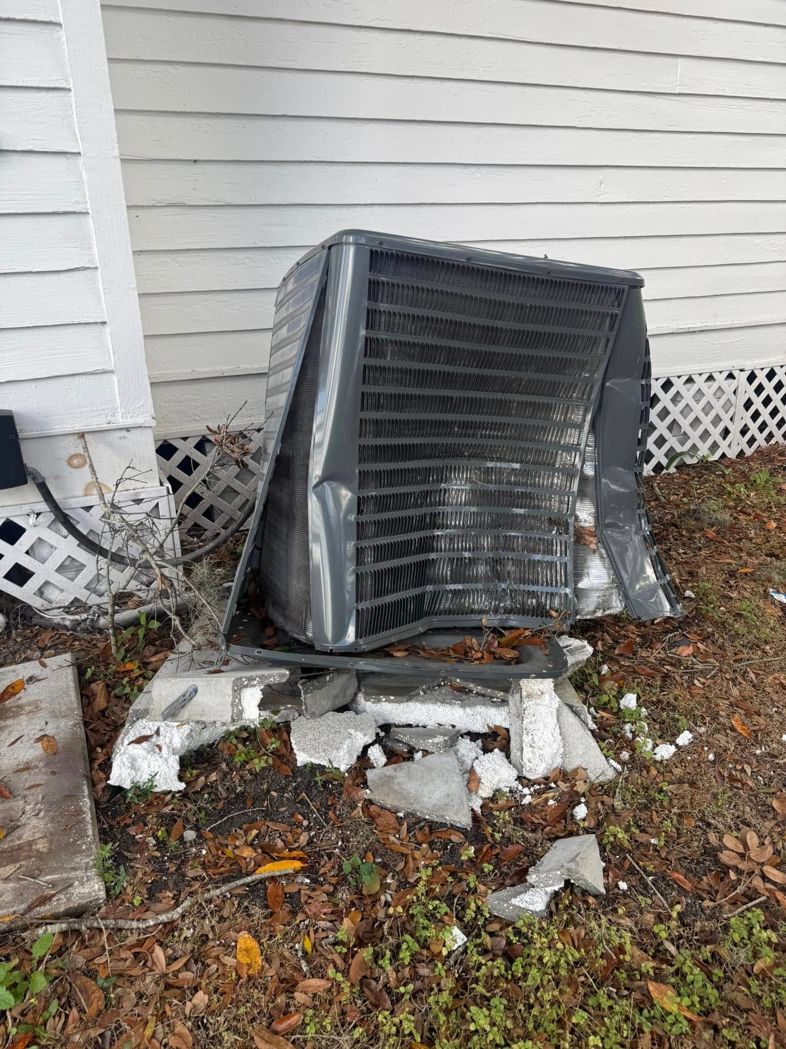 A broken air conditioner is sitting on the ground in front of a house.