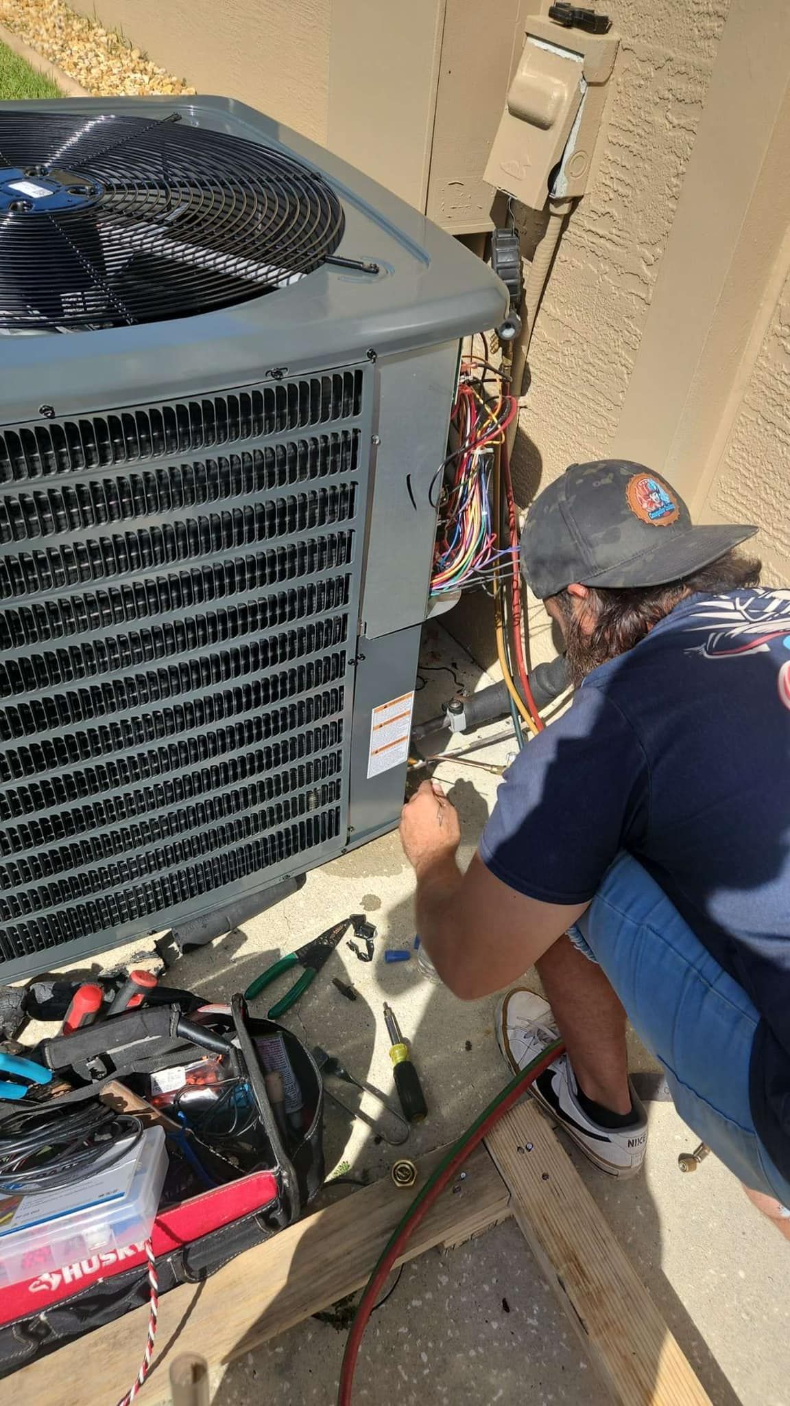 A man is working on an air conditioner outside of a building.