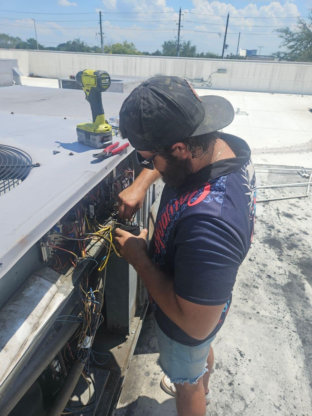 A man is working on an air conditioner with a drill.