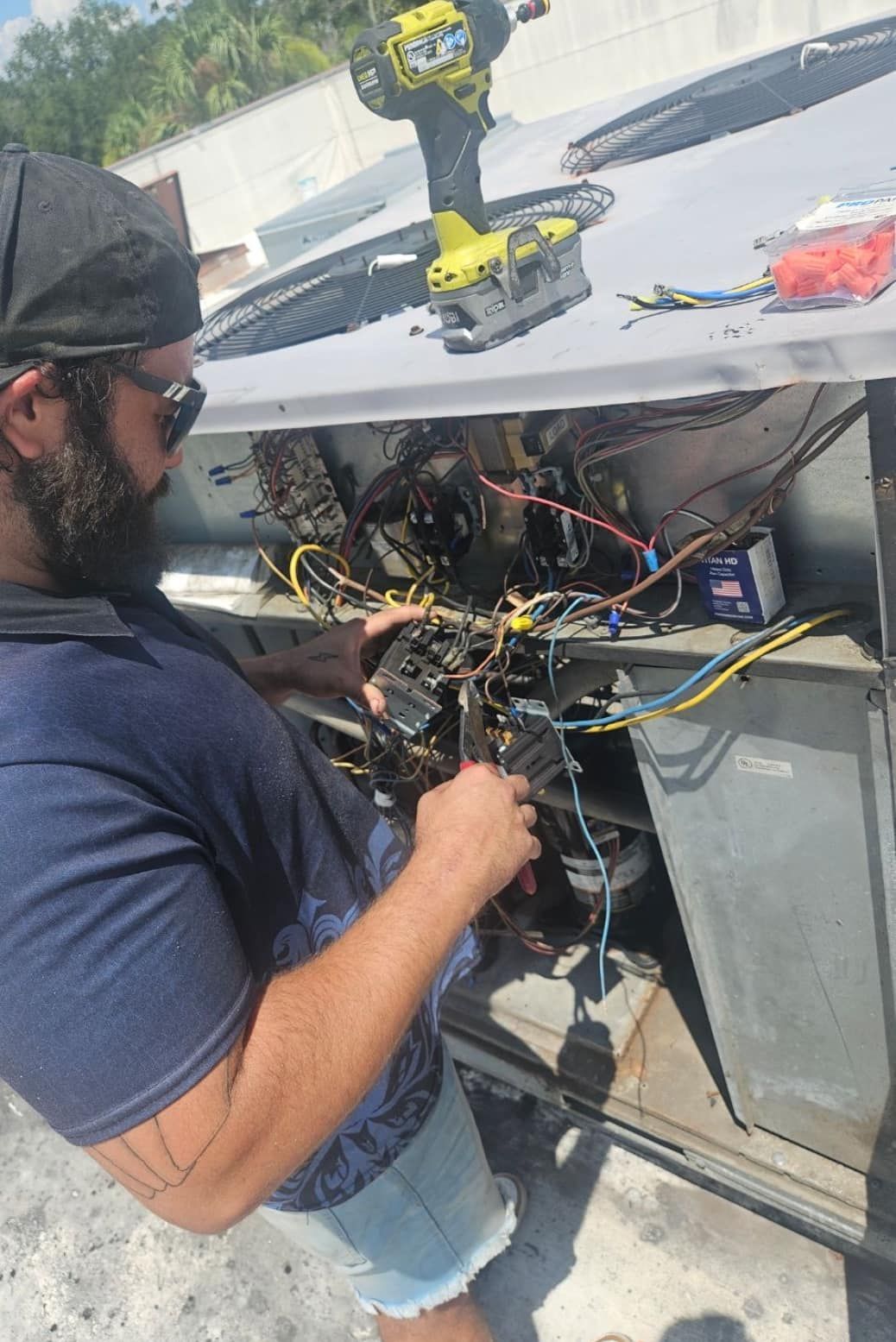 A man is working on an air conditioner with a drill.