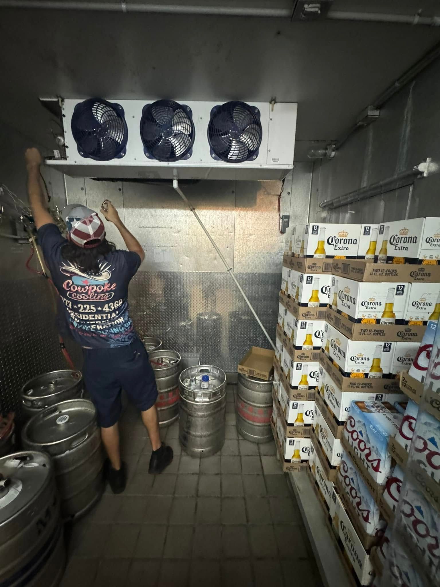 A man is standing in a room filled with kegs and boxes of coors light beer.
