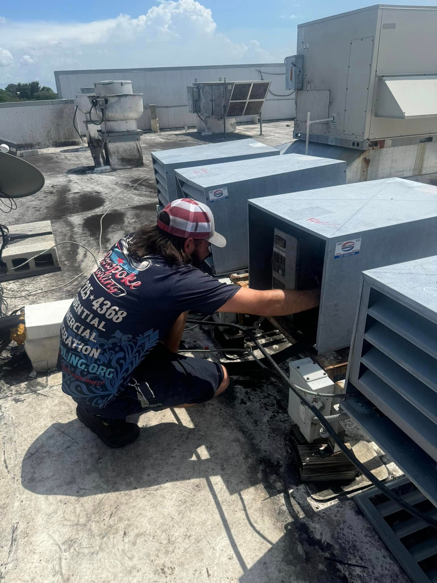 A man is working on an air conditioner on the roof of a building.