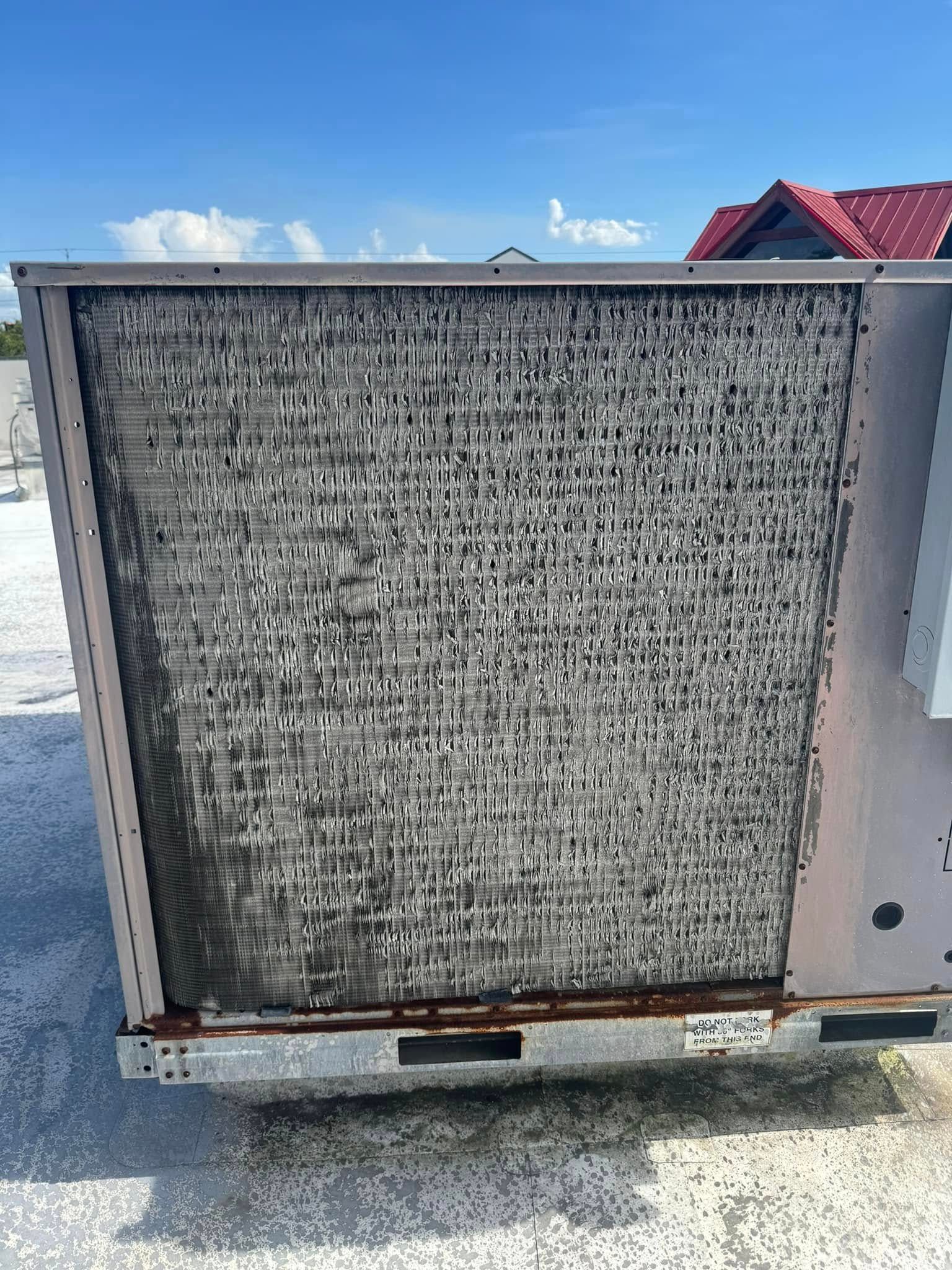 A dirty air conditioner is sitting on top of a concrete surface.